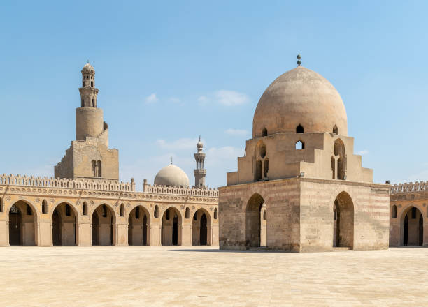 Courtyard of Ibn Tulun public historical mosque, Cairo, Egypt. View showing the ablution fountain, and the minaret Courtyard of Ibn Tulun public historical mosque, Cairo, Egypt. View showing the ablution fountain, the minaret and the minaret of Sarghatmish mosque ancient arch architecture brick stock pictures, royalty-free photos & images