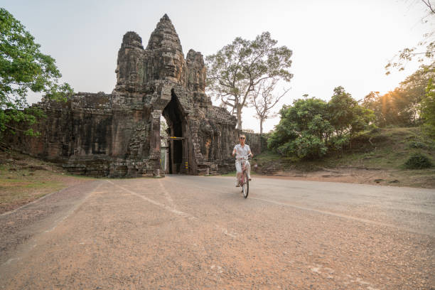 istock Young woman on bicycle in ancient temple complex in Cambodia 989512184