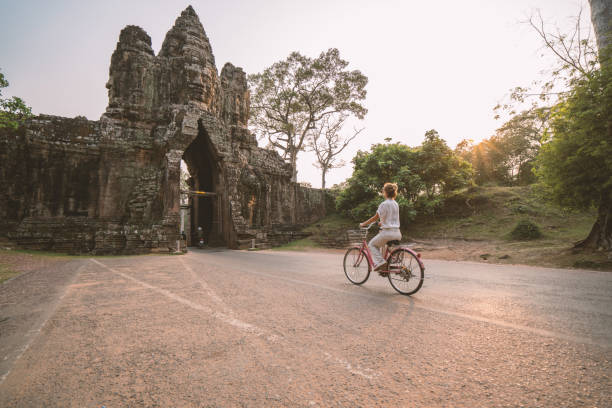 istock Young woman on bicycle in ancient temple complex in Cambodia 989512404