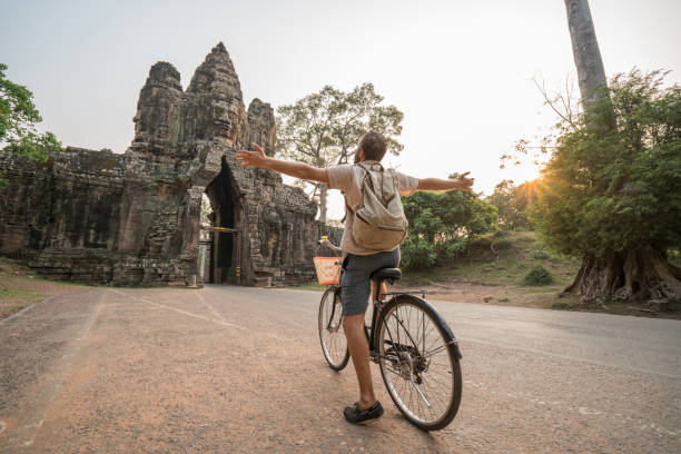 istock Young man on bicycle in ancient temple complex in Cambodia 989512842