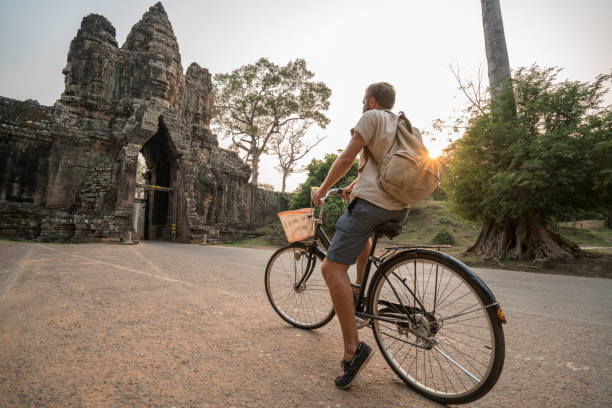 istock Young man on bicycle in ancient temple complex in Cambodia 989513112