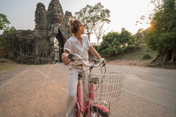 istock Young woman on bicycle in ancient temple complex in Cambodia 989513118