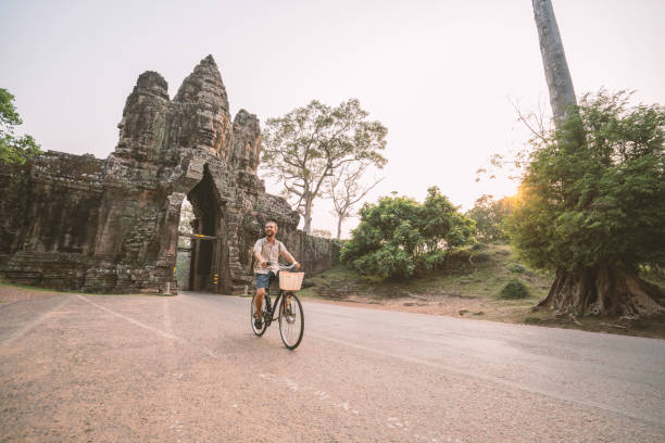 istock Young man on bicycle in ancient temple complex in Cambodia 989513228