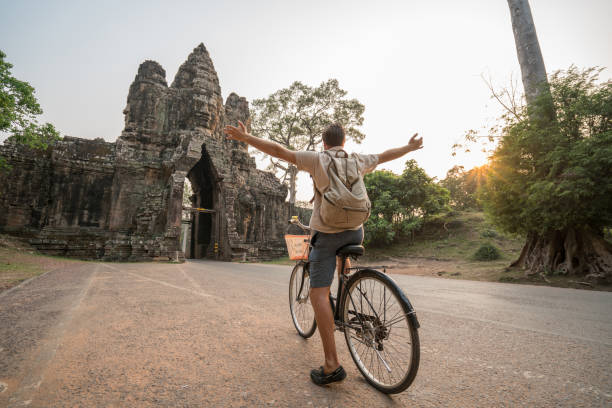 istock Young man on bicycle in ancient temple complex in Cambodia 989513230