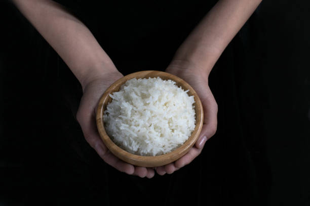 istock Holding a wooden  bowl of  cooked rice 989516524
