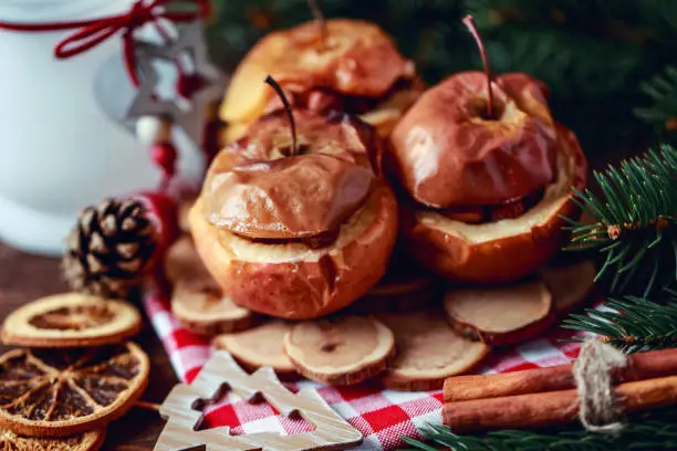 Baked apples with cinnamon on rustic background. Autumn or winter dessert. Closeup photo of a tasty baked apples with Christmas decoration