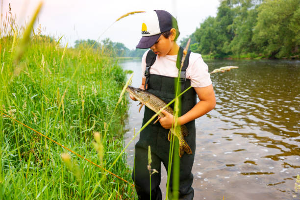 istock Young fisherman holding a pike he has just caught. 989564438