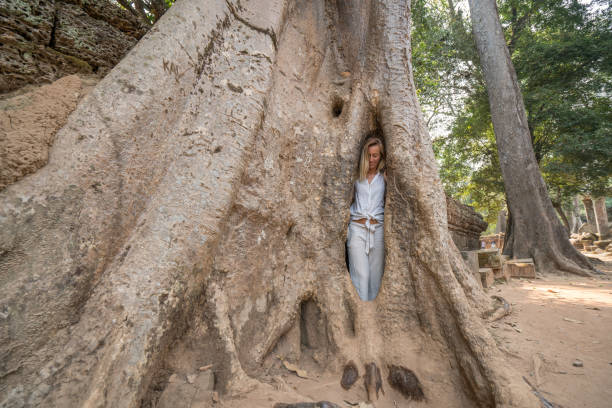 istock Girl in ancient temple complex hiding in enormous tree, big roots 989570930
