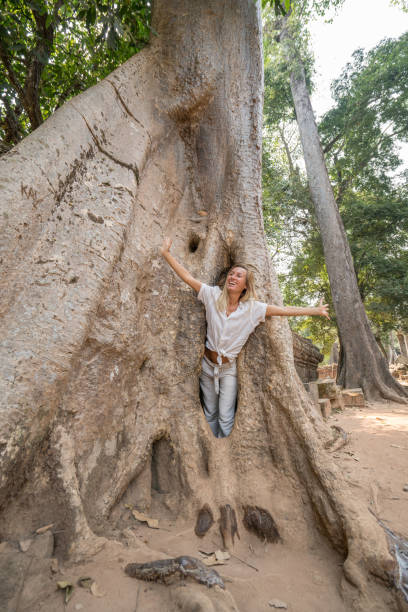 istock Girl in ancient temple complex hiding in enormous tree, big roots 989575822