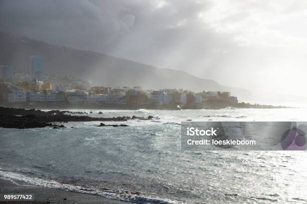 Sunrays Over The Coastline With Houses During Sunset At The Black Beach At Puerto De La Cruz Tenerife Canary Islands Spain Stock Photo - Download Image Now
