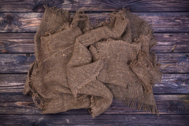 istock Burlap on black wooden background, top view 989620028