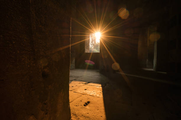 View from inside ancient temple at sunset, sunbeam coming through window \nAngkor Wat, Siem Reap, Cambodia