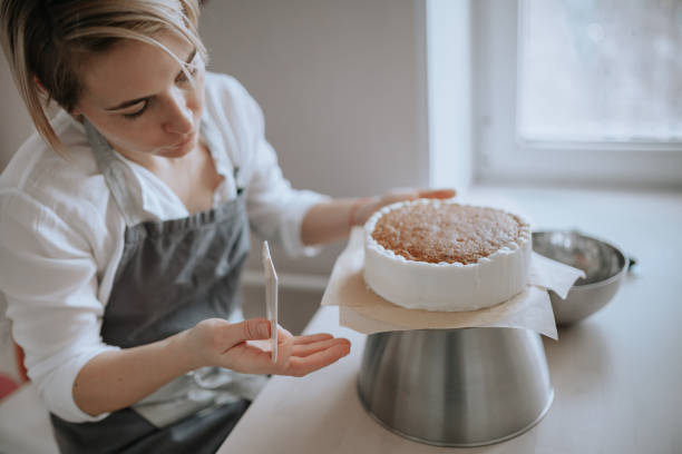 Young female pastry chef or a baker preparing a cake. stock photo