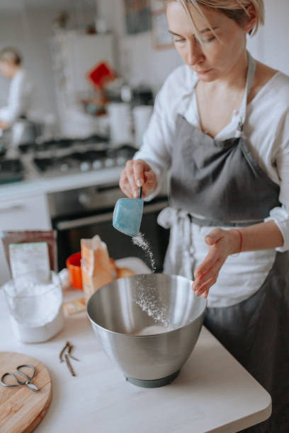 istock Young female pastry chef or a baker preparing a cake. 989651764
