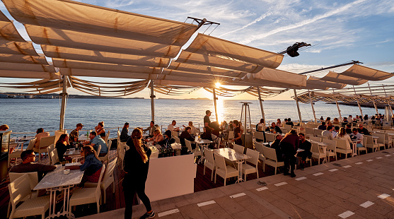 Ibiza Island, Spain - May 1, 2018: Crowds of people meet the sunset at the seafront terrace of Savannah cafe, located on the West Coast of Ibiza. This place is famous for views to the sunsets and lounge music. Ibiza, Balearic Islands. Spain