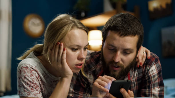istock Young couple surfing smartphone on bed 989659968