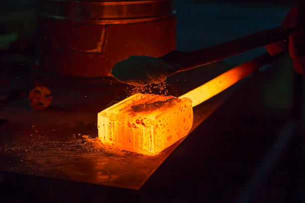 Glowing iron ingot on the table. Hot metal workpiece for the manufacture of Damascus steel. stock photo
