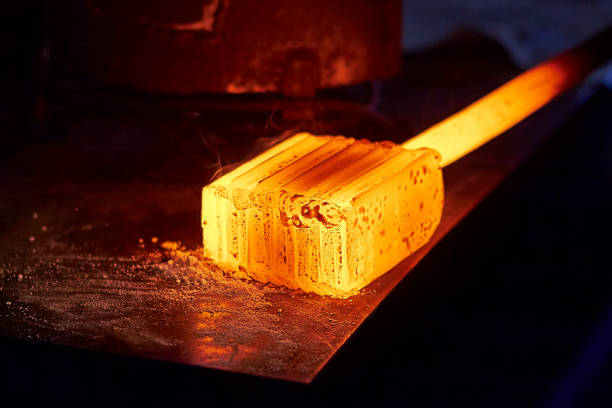 Glowing iron ingot on the table. Hot metal workpiece for the manufacture of Damascus steel. stock photo