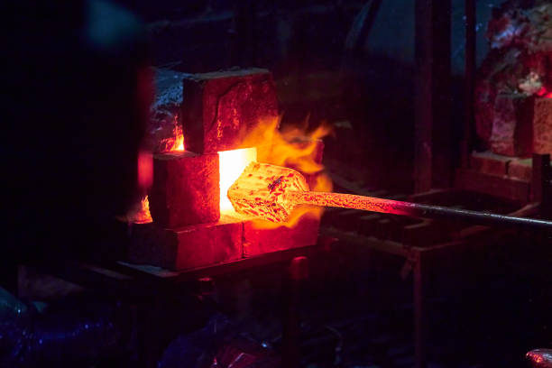 Hot item is inserted into the blacksmith's forge from which the tongues of flame. Concept: blacksmithing, forge stock photo