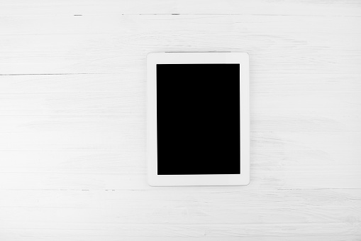 Big Black Empty Screen Smart Tablet Device With White Frame On White Wooden Background  Top Angle