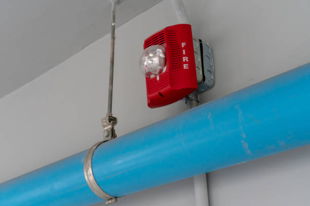 istock Red Fire alarm lighting above blue PVC pipe against white background 989671504
