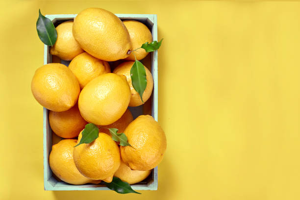 istock Yellow lemons in a box on a yellow background. The view from the top. Space for text, copy space 989678040