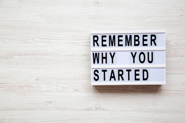 istock 'Remember why you started' words on lightbox over white wooden background, from above. Copy space. 989713918
