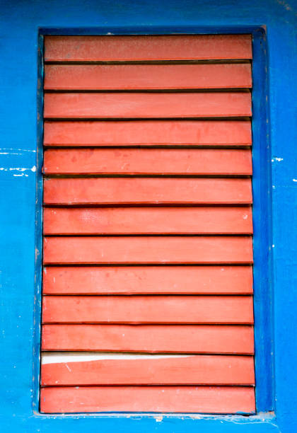 contraventanas de madera rojo cerraron en la ventana en la pared azul - wood shutter rusty rust fotografías e imágenes de stock