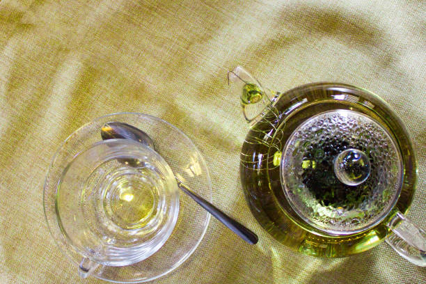 istock Beverages, good morning and breakfast concept - empty tea cup and teapot with green tea on the table 989722218