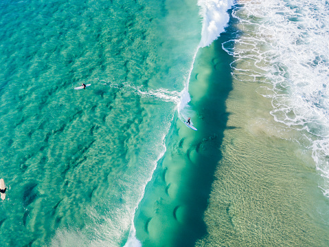 Surfers at the beach waiting for a wave on a clear day with clear blue/turquoise water