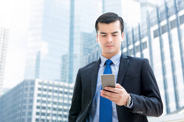istock Businessman looking at mobile phone screen, outdoors in the city 989794664