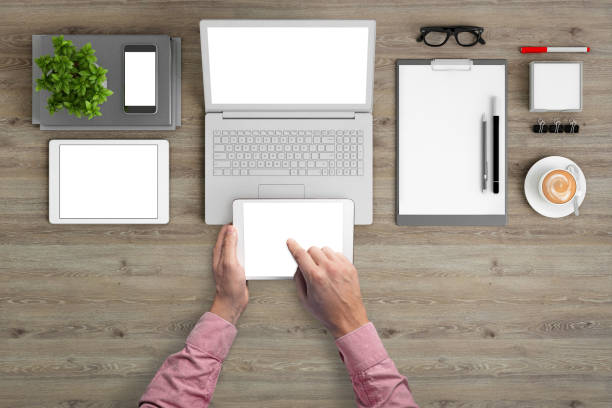 istock Man holding tablet knolling overhead view 989794800