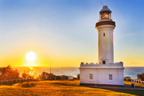 Warm filling sun light rising above open sea horizon off Pacific ocean behind Norah head lighthouse on Australian's central coast.