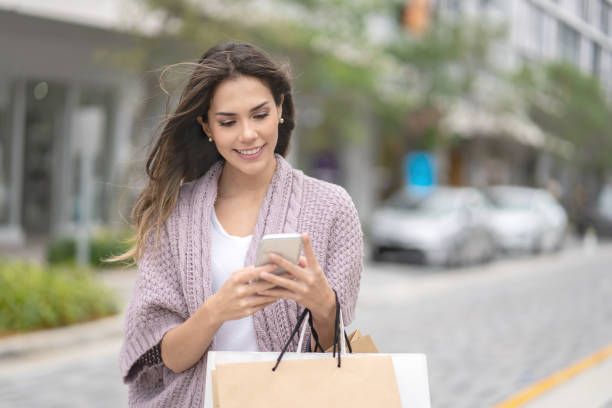 istock Beautiful shopping woman using app on her cell phone 989813732
