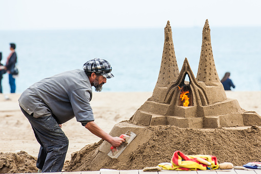 BARCELONA - MARCH, 2018: Sand sculptor working at La Barceloneta Beach in Barcelona Spain