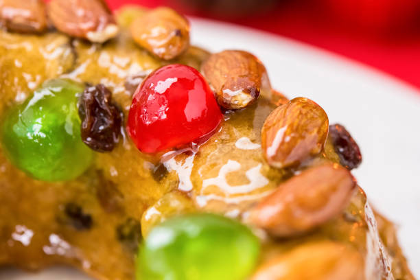 Close up of glazed colorful Christmas fruitcake topped with almonds and glace cherries