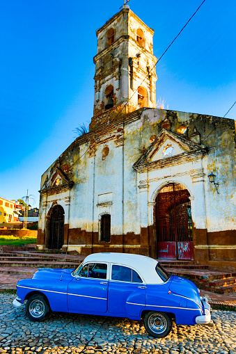 Trinidad, Cuba, Nov 28, 2017 - Blue Classic 1950's Chevrolet is parked in front of abaondoned church