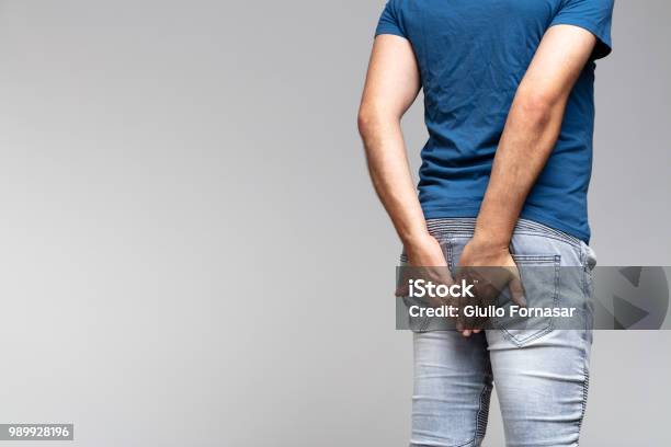 Caucasian Man Holding His Buttocks In Denim Jeans Stock Photo - Download Image Now - Buttocks, Men, Pants