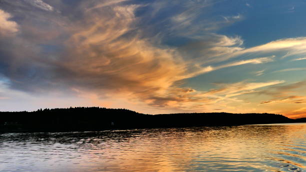 istock Sunset that illuminates the water and clouds above the mountain 989944576
