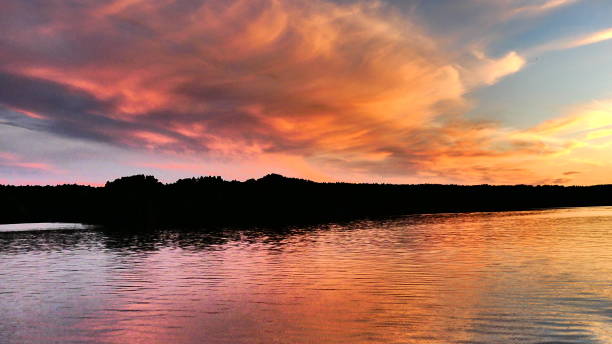 istock Sunset over the mountain tinged pink and bright orange with reflections on the water 989945100