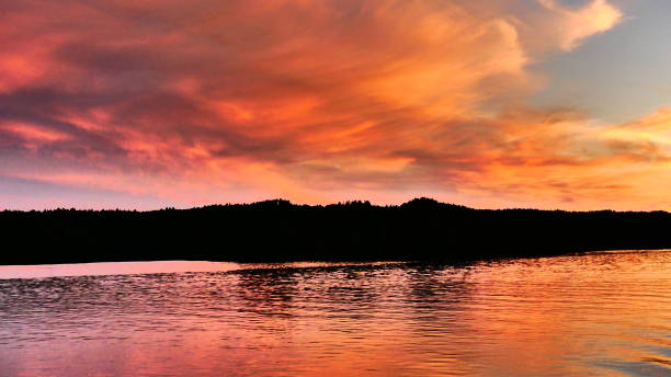 istock Sunset tinged with bright pink and orange with reflections on the water 989945546