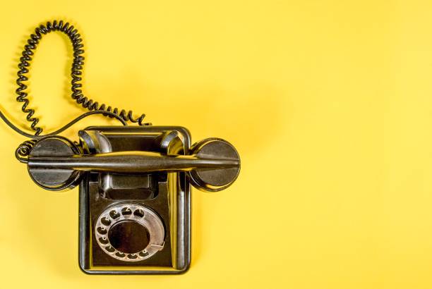 istock Vintage black telephone on yellow 989972428
