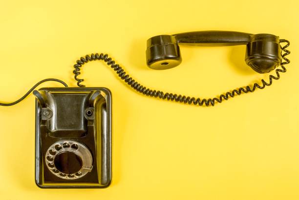 istock Vintage black telephone on yellow 989972430