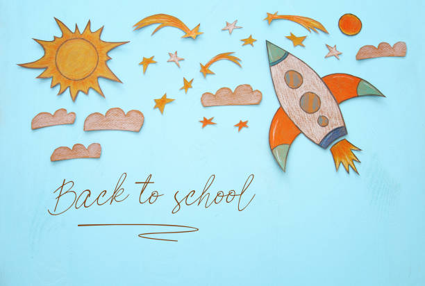 istock Rocket cut from paper and painted over wooden blue background. 989991840