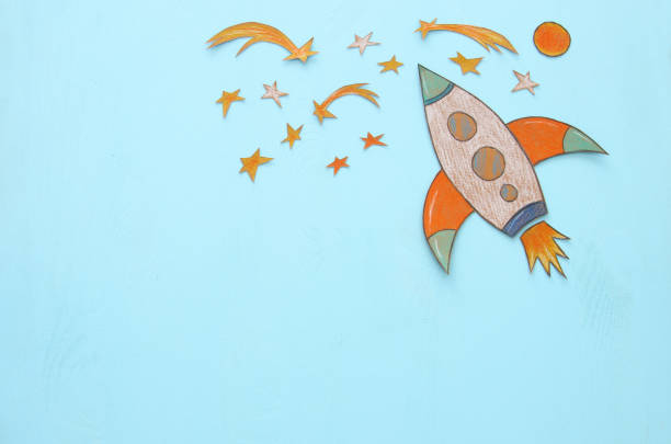 istock Rocket cut from paper and painted over wooden blue background. 989992044