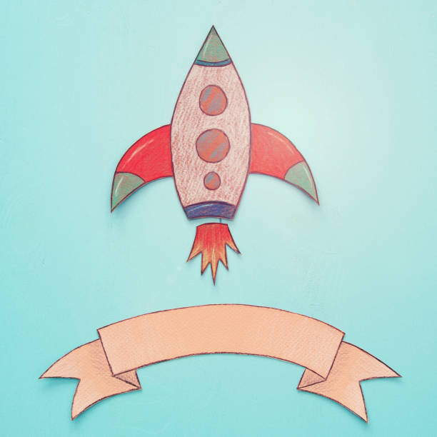 istock Rocket cut from paper and painted over wooden blue background. 989993084