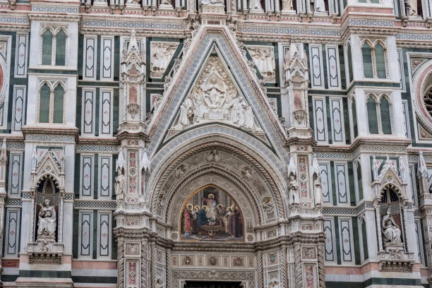 detalhe da parte superior da porta principal da catedral de santa maria del fiore, com um afresco pintado no arco superior e rodeado por colunas de mármore de pilares - pillared - fotografias e filmes do acervo