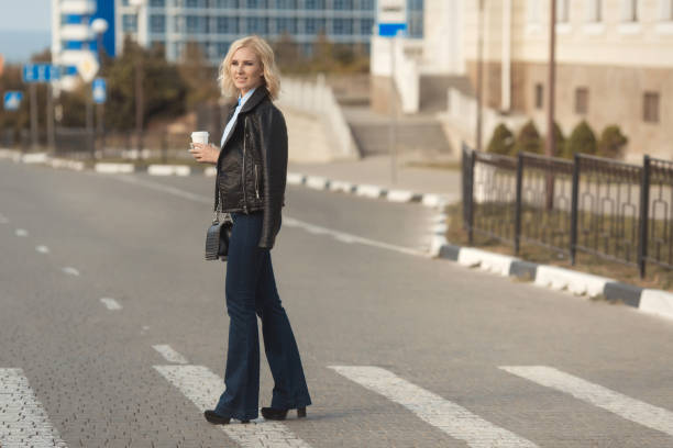 Beautiful blonde woman cross the road with a take away coffee. Street fashion look. Beautiful blonde woman cross the road with a take away coffee. Street fashion look. flare pants stock pictures, royalty-free photos & images