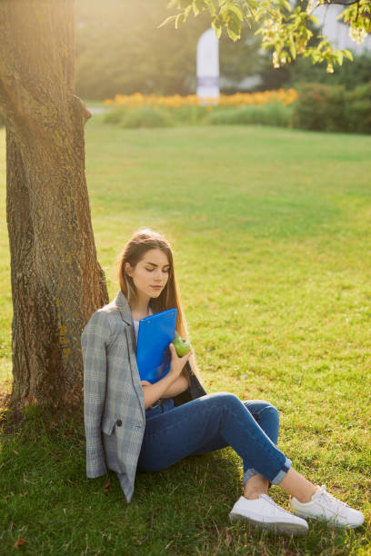 istock Pretty girl with her book in park background, sunset 990083064