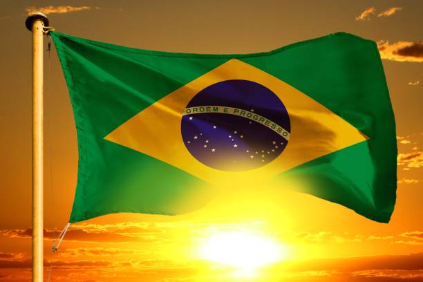 istock Brazil flag weaving on the beautiful orange sunset with clouds background 990086534